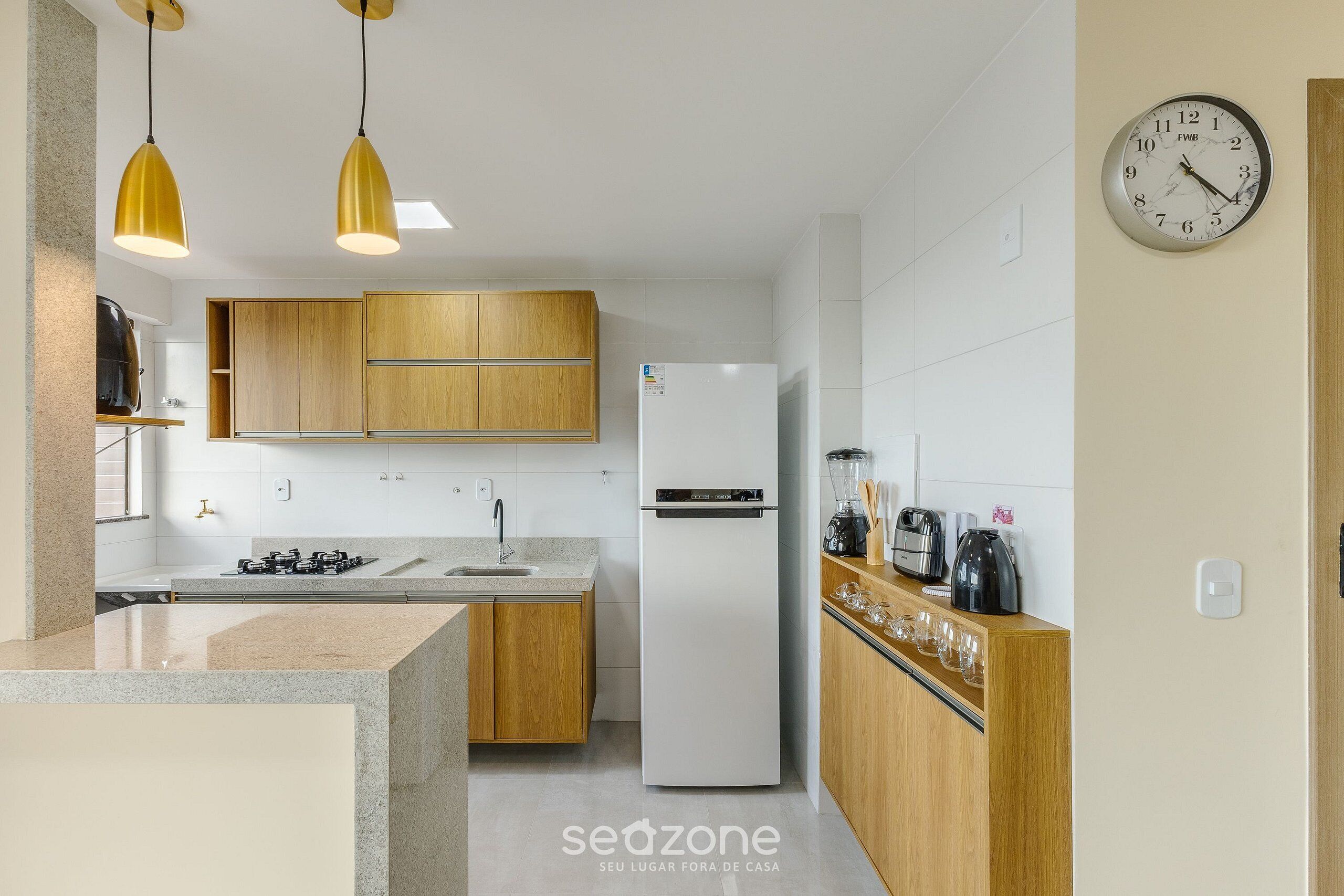 A modern kitchen with wooden cabinets, a white refrigerator, and a clock on the wall.