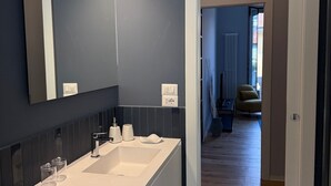 Ein modernes Badezimmer mit einem Waschbecken-Doppelplatz, einem großen Spiegel und einer begehbaren Dusche.