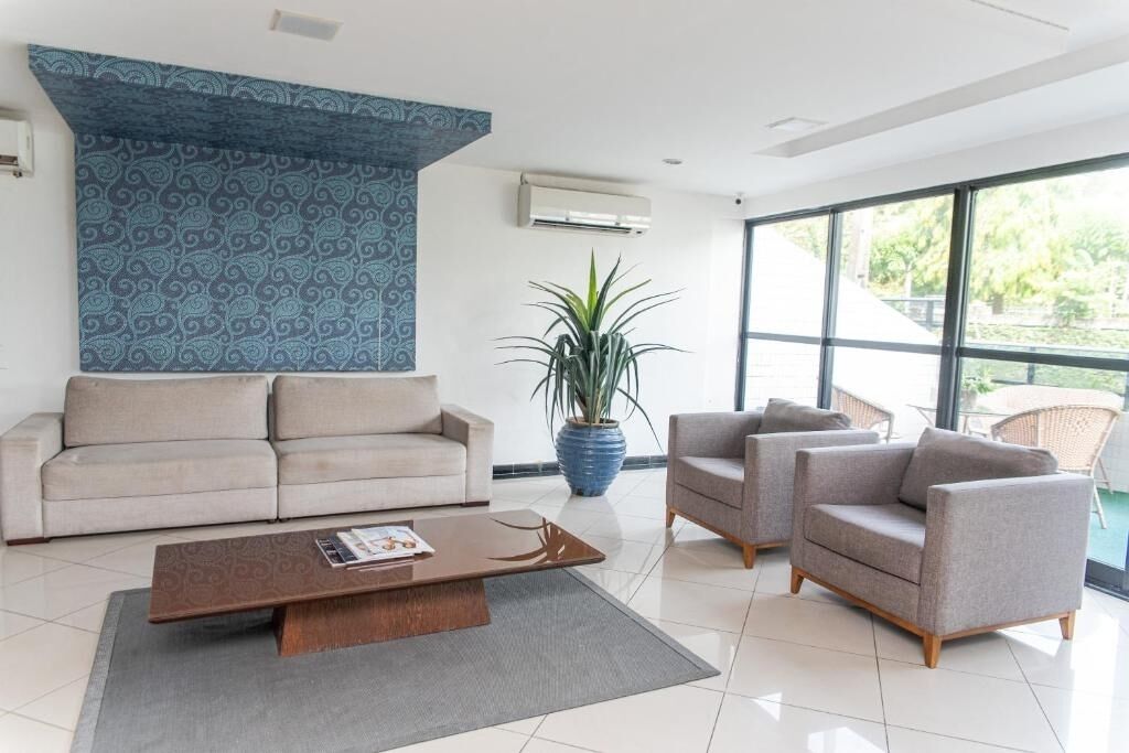 A modern living room with a sofa, two armchairs, a coffee table, and a large window with a view of greenery.