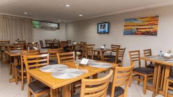 A dining area with wooden tables and chairs, arranged in a spacious layout.