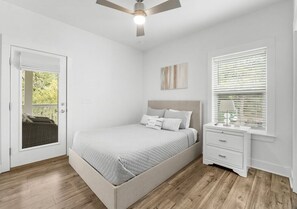 A bedroom with a bed, a nightstand, a window with blinds, a ceiling fan, and a door leading to an outdoor area. - Lucky Snapper - 30A Coastal Retreat with 6-Seater Golf Cart (Santa Rosa Beach)