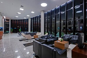 Een moderne lobby met een gebogen glazen wand, lederen zitplaatsen en een receptiebalie.