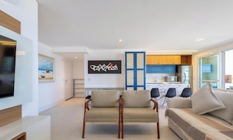 Una sala de estar moderna con un televisor de pantalla plana, un sofá y dos sillones.