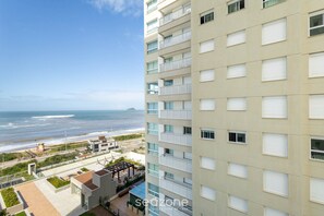 Um edifício alto com várias varandas e vista para a praia.