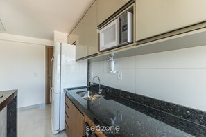 A modern kitchen with a refrigerator, microwave, and stainless steel sink. - Apt. With sea View in Bldg. With Pool Mmd0605 (Ilhéus)