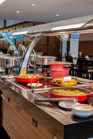 A buffet setup with various dishes and cooking equipment. - Prime Location in Palhoça | Work-Friendly Unit | Pets Allowed (Santa Catarina)