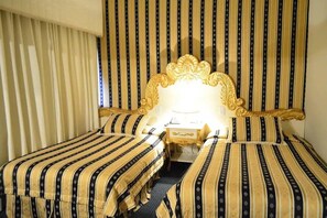 Een hotelkamer met twee bedden, een groot versierd hoofdeinde en gestreepte gordijnen.