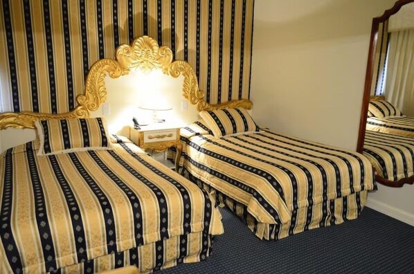 Een hotelkamer met twee bedden, een grote sier spiegel en een nachtkastje met een lamp.