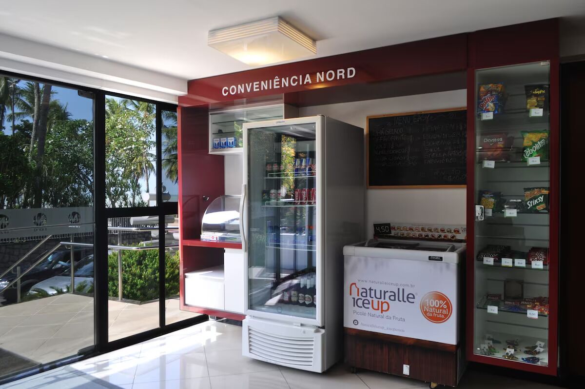 A convenience store with a glass display case, a freezer, and a vending machine labeled "natural ice up."