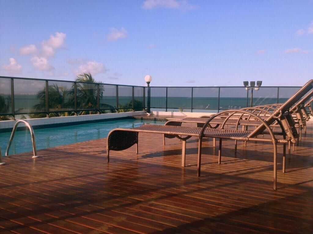 A poolside area with lounge chairs and a view of the ocean.