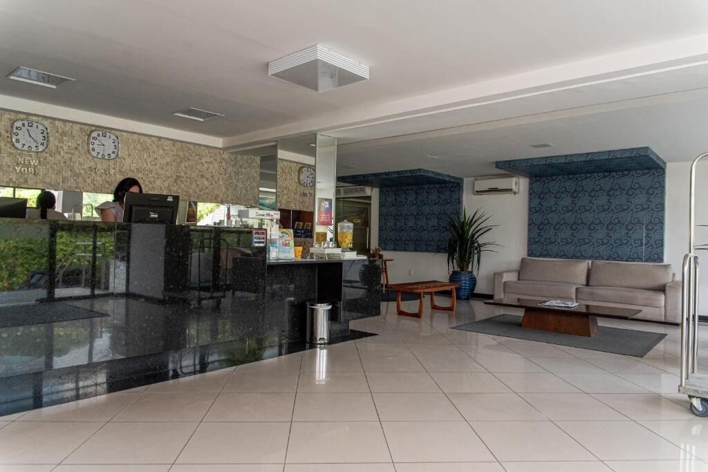 A hotel lobby with a reception desk, a sofa, a coffee table, and a clock on the wall.