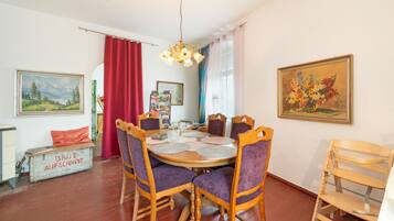 A dining area with a round table, wooden chairs, and a red curtain.