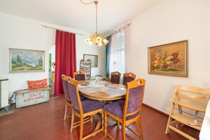 A dining area with a round table, wooden chairs, and a red curtain.
