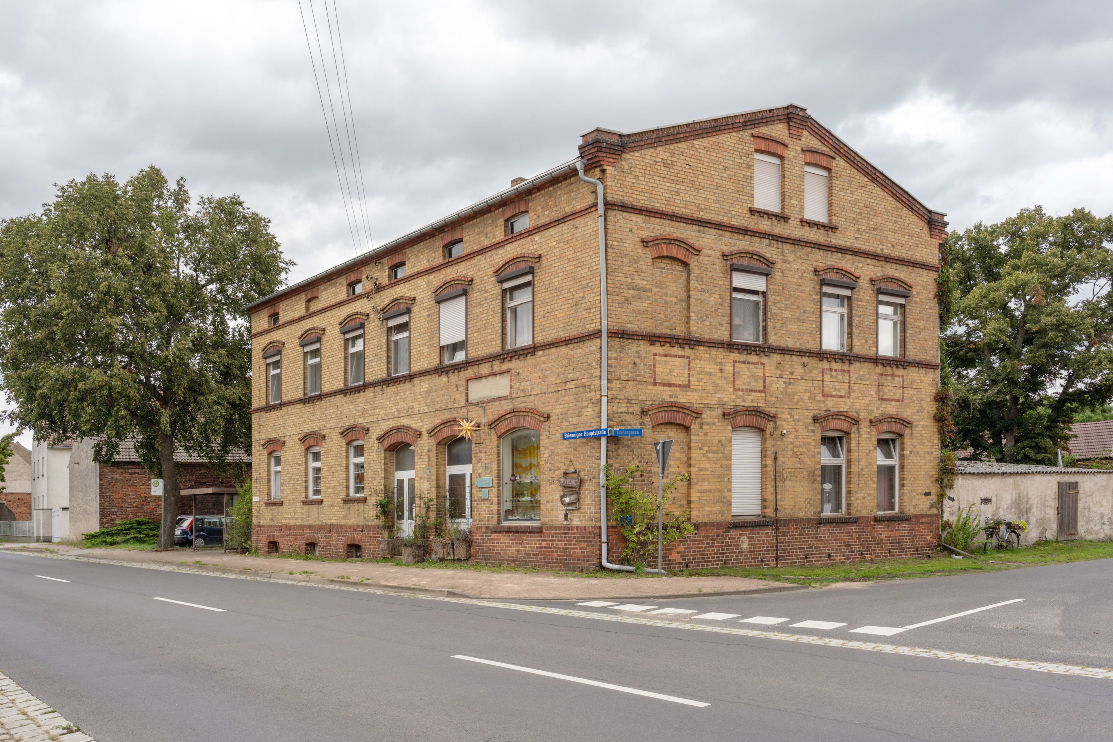 Ein zweistöckiges Backsteingebäude mit zahlreichen Fenstern und einer Straße davor.