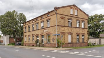 Ein zweistöckiges Backsteingebäude mit zahlreichen Fenstern und einer Straße davor.