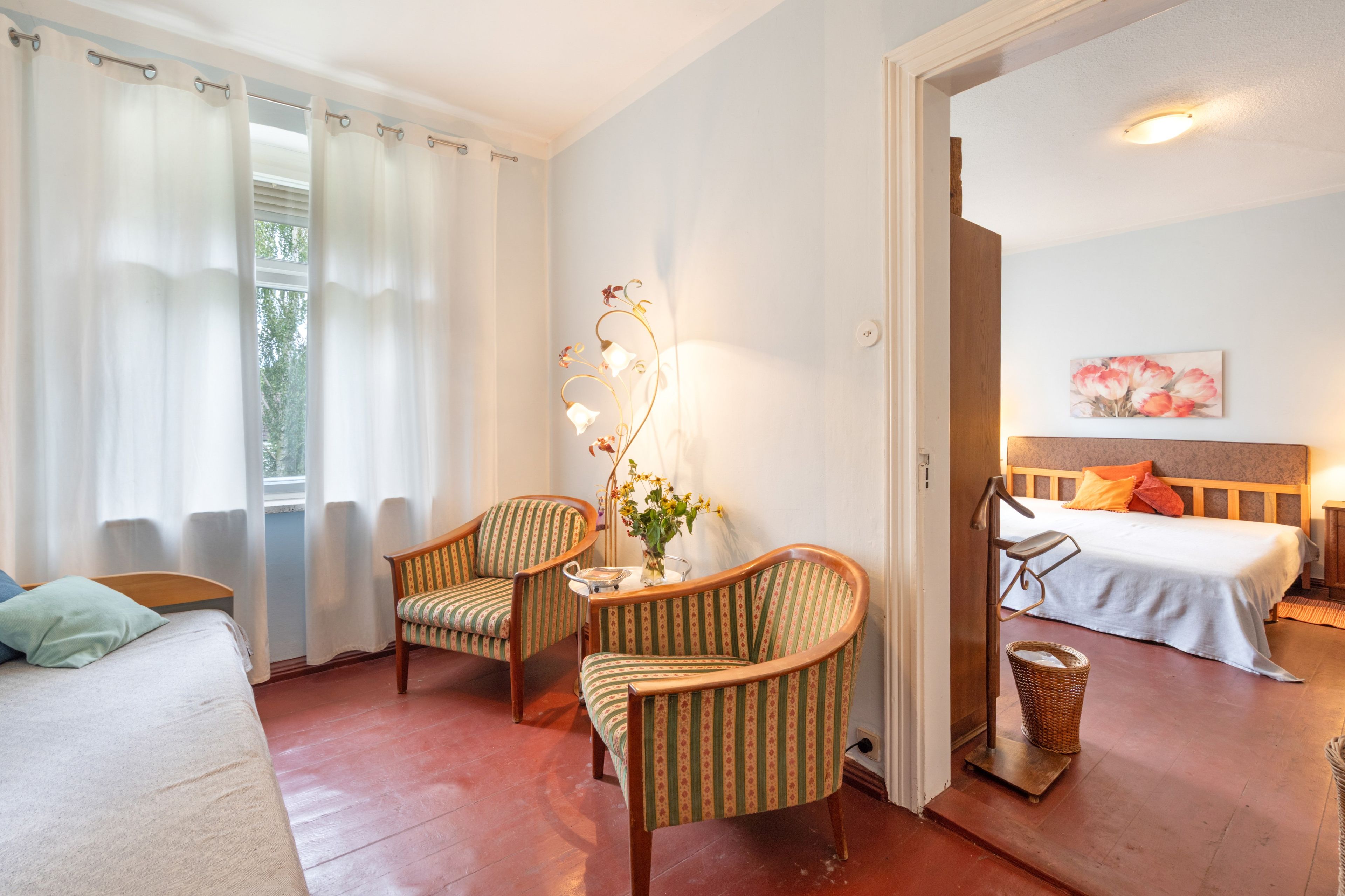 Une pièce avec deux chaises, un lit, une table de chevet et un tableau accroché au mur.