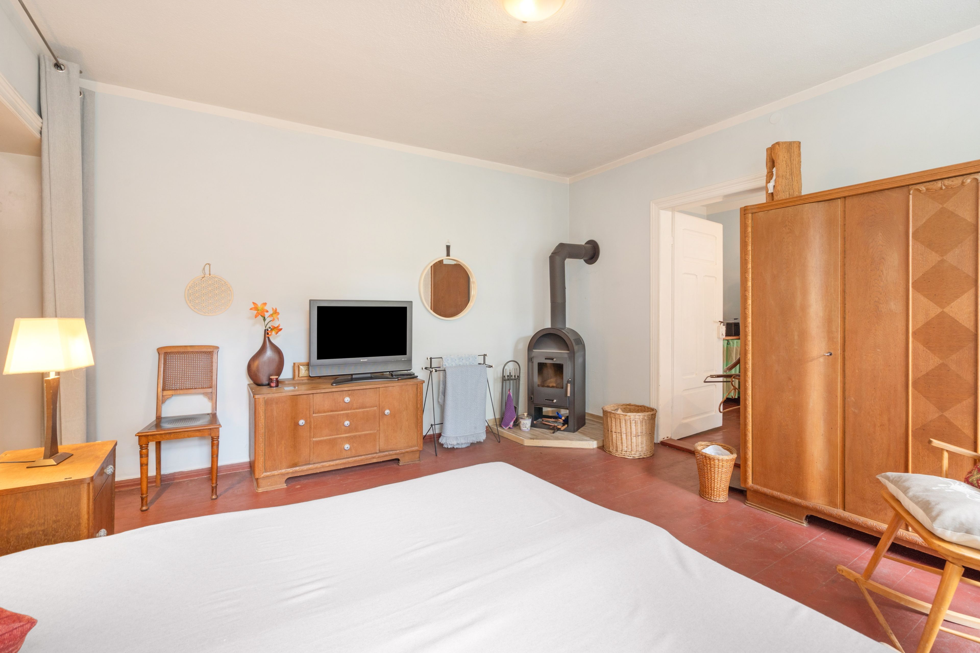 A bedroom with a bed, a TV, a fireplace, a wardrobe, and a chair.