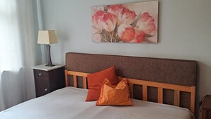 Ein Schlafzimmer mit einem Bett, einem Nachttisch, einer Lampe und einem Bild an der Wand.