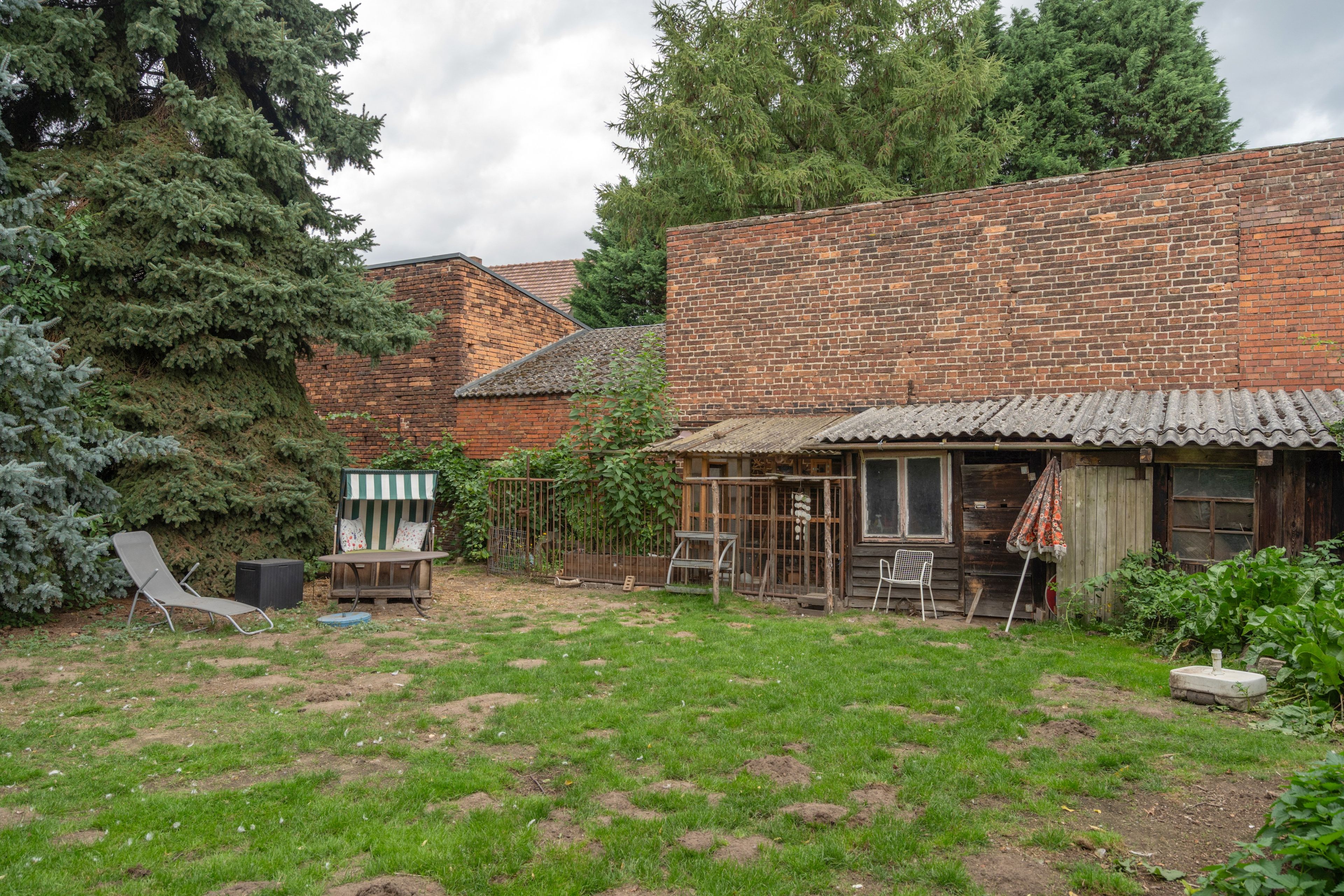 Une cour arrière rustique avec une maison en briques, une balançoire et un jardin.