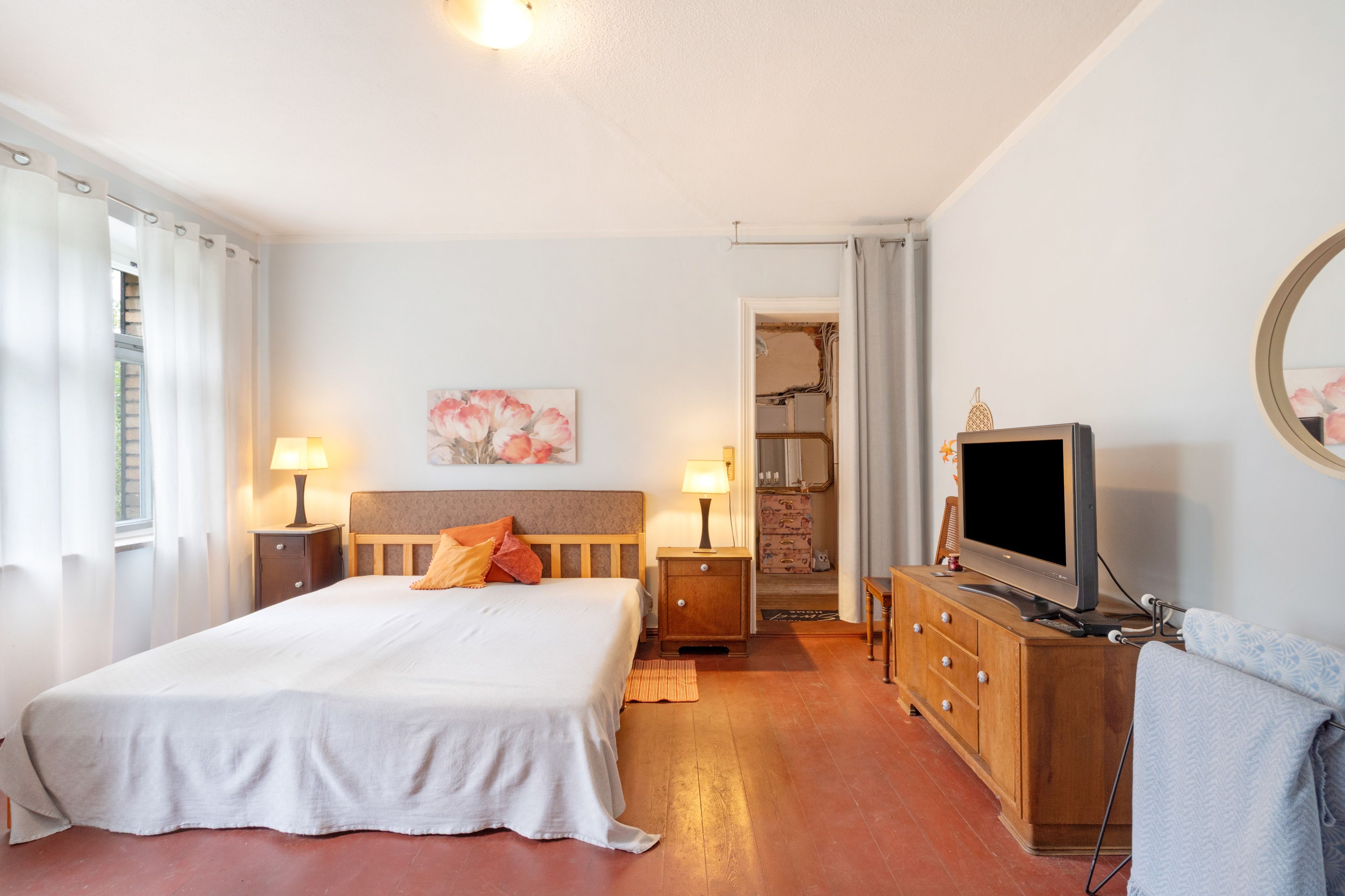 Une chambre d’hôtel avec un grand lit, des lampes de chevet, une télévision et un tableau au mur.