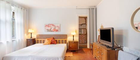 A hotel room with a large bed, bedside lamps, a television, and a painting on the wall.