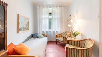 Une chambre à coucher avec un lit, une chaise, une table, une lampe et un tableau accroché au mur.