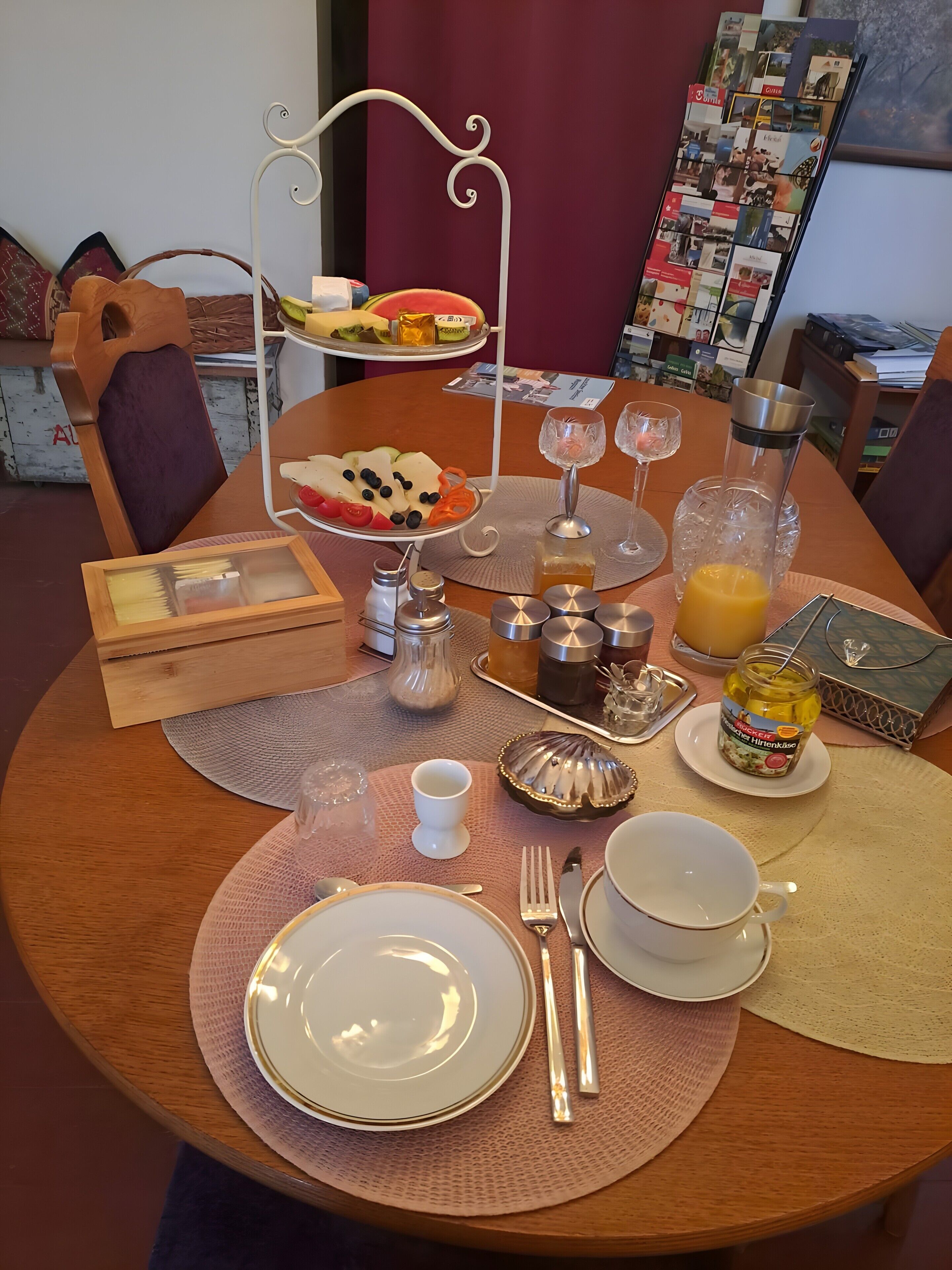 A dining table set with plates, cutlery, a fruit platter, glasses, and condiments.