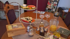A dining table set with plates, cutlery, a fruit platter, glasses, and condiments. - Apartment ',,Dresden Hellerau,,' with Shared Terrace, Private Garden and Wi-Fi (Forst (Lausitz))