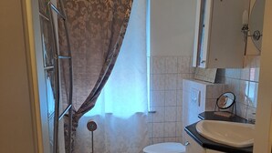A bathroom with a toilet, sink, and shower curtain. - Apartment ',,Dresden Hellerau,,' with Shared Terrace, Private Garden and Wi-Fi (Forst (Lausitz))