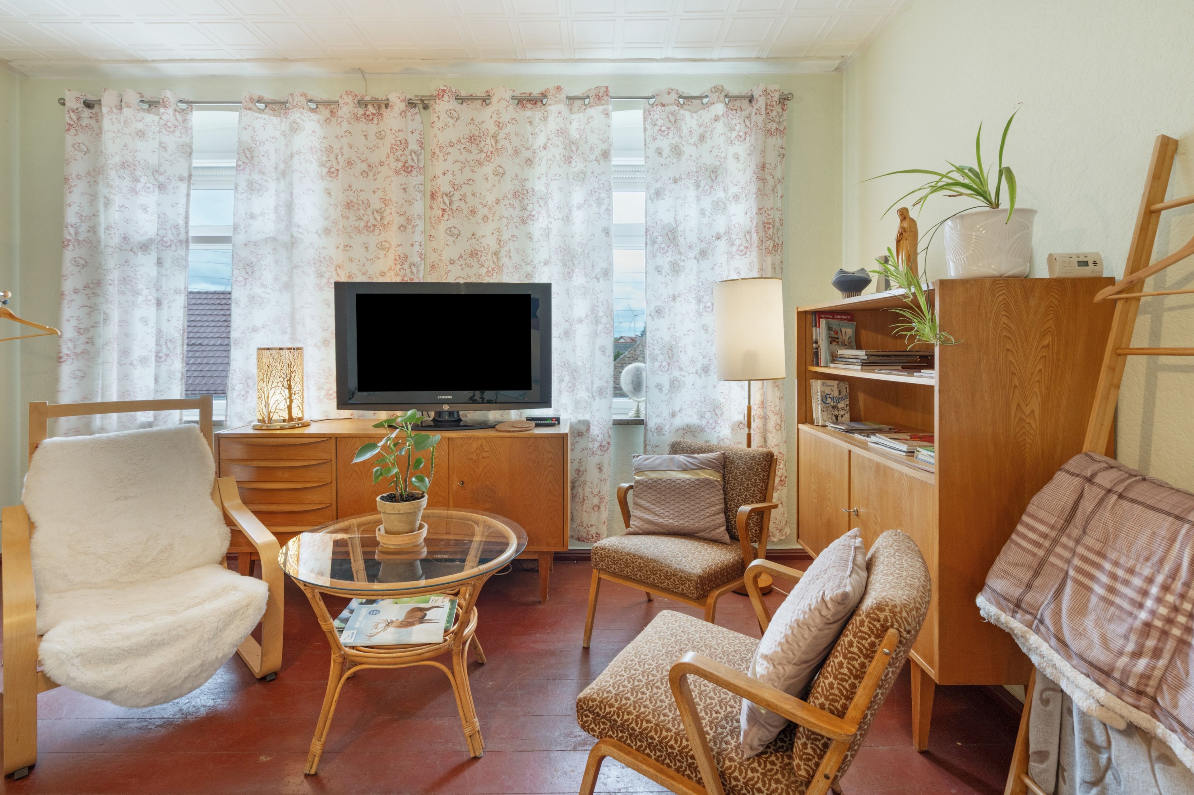 Una sala de estar con televisor, sofá, sillón, mesa y estantería.