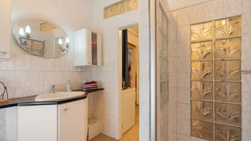 A bathroom with a sink, mirror, cabinet, and a shower area with decorative glass panels.