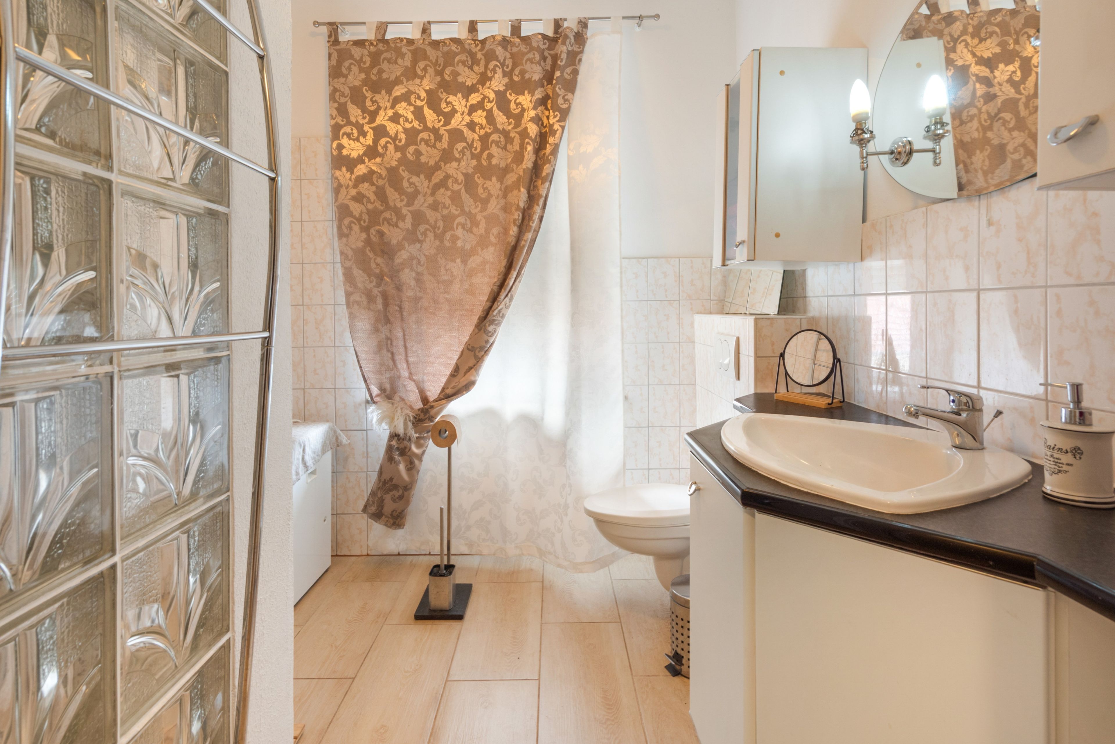 A bathroom with a glass shower enclosure, a toilet, a sink with a mirror above it, and a towel rack.