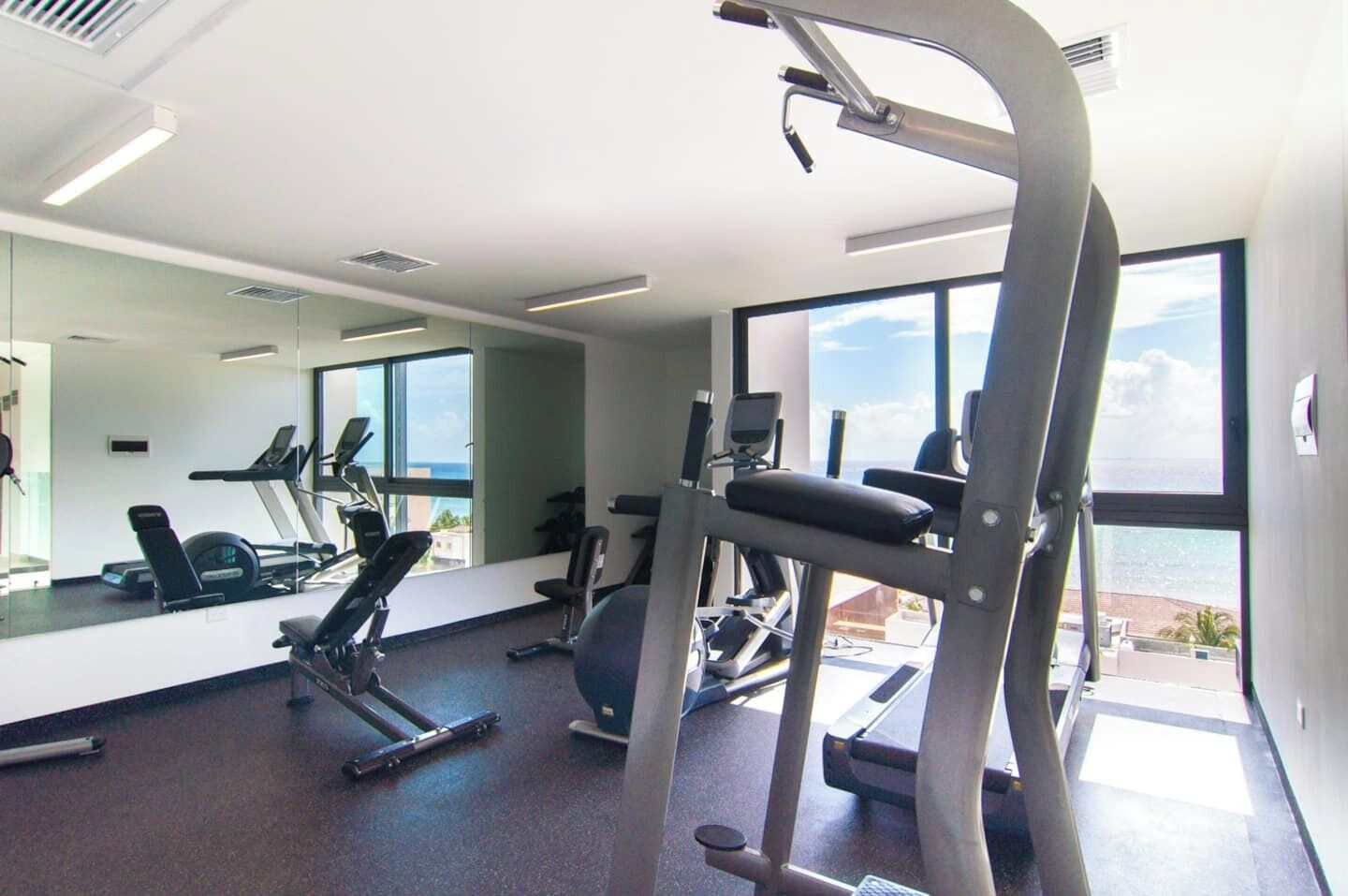 A gym with exercise equipment, large windows, and a view of the outdoors.