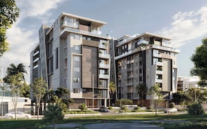 Een modern appartementencomplex met meerdere verdiepingen, balkons, een aangelegde tuin en een heldere lucht.