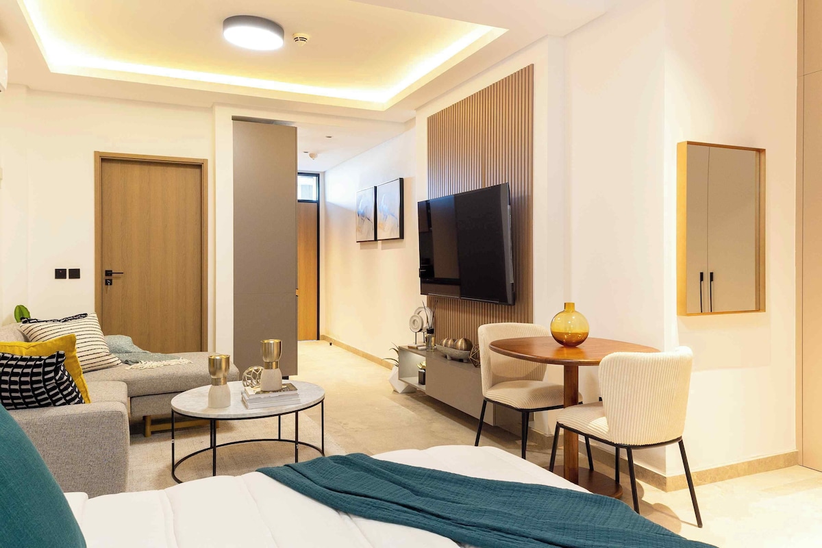 Een hotelkamer met een bed, een bank, een eettafel en een televisie.