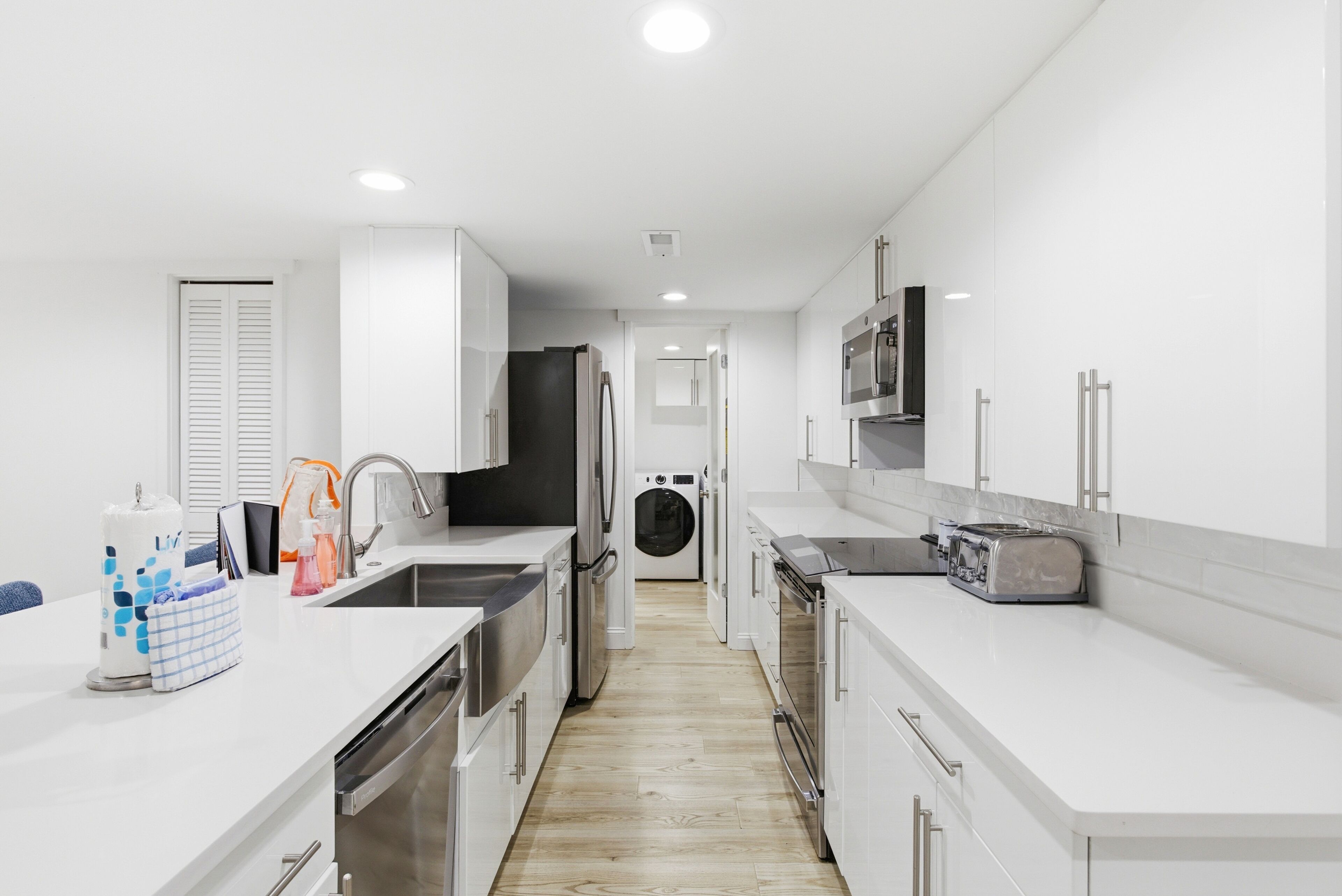 Una cocina moderna con armarios blancos, electrodomésticos de acero inoxidable y una isla central con fregadero.