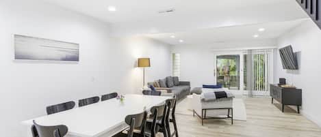 A modern interior with a dining area, seating, and a staircase.