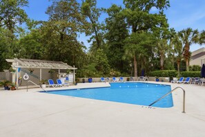 A swimming pool with blue tiles, surrounded by lounge chairs and potted plants. - Sunset Rentals | Sailmaster 46 (Hilton Head Island)