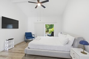 A modern bedroom with a bed, a chair, a desk, and a ceiling fan. - Sunset Rentals | Sailmaster 46 (Hilton Head Island)