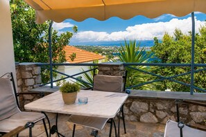 Une terrasse avec une table et des chaises, un pot de fleurs et une vue sur un paysage côtier.