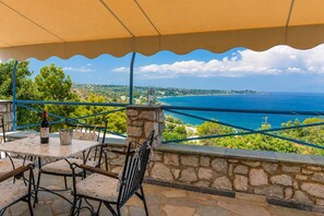 Un espace extérieur aménagé avec des murs en pierre, une table, des chaises et une vue sur la mer.