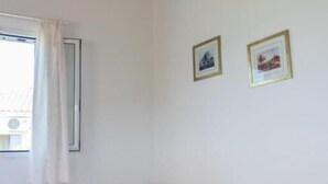 A room with a wooden ceiling, two beds, a window with curtains, and two framed pictures on the wall. - Koroni Akrita Residence, Venetico Seafront Charm (Koroni)