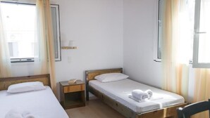 A hotel room with two single beds, a bedside table with a lamp, and a window with curtains. - Koroni Akrita Residence, Venetico Seafront Charm (Koroni)