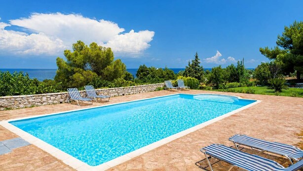 A rectangular swimming pool with a stone border, surrounded by lounge chairs and a stone wall. - Koroni Akrita Residence, Venetico Seafront Charm (Koroni)