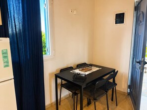 Un petit coin repas avec une table, des chaises et une fenêtre.