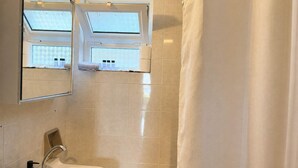 Ein Badezimmer mit einem großen Spiegel, einem Waschbecken und einem Fenster.