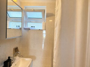 Une salle de bain avec un grand miroir, un lavabo et une fenêtre.
