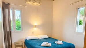 Ein Schlafzimmer mit einem Bett, einem Nachttisch, einer Wandleuchte und einem Fenster mit Vorhängen.