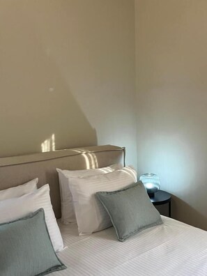 Une chambre d’hôtel avec un lit, des oreillers, une table de chevet et une lampe.