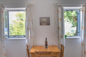 Een eethoek met een tafel, stoelen, een fles en een schilderij aan de muur.